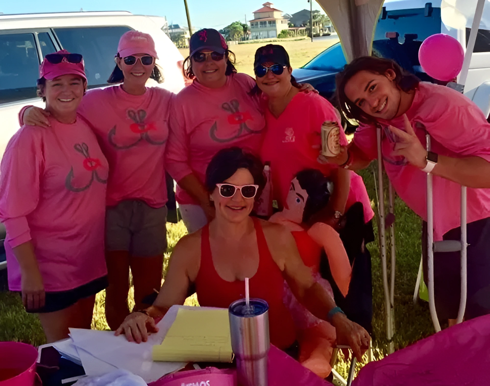 Group in pink shirts smiling outdoors.